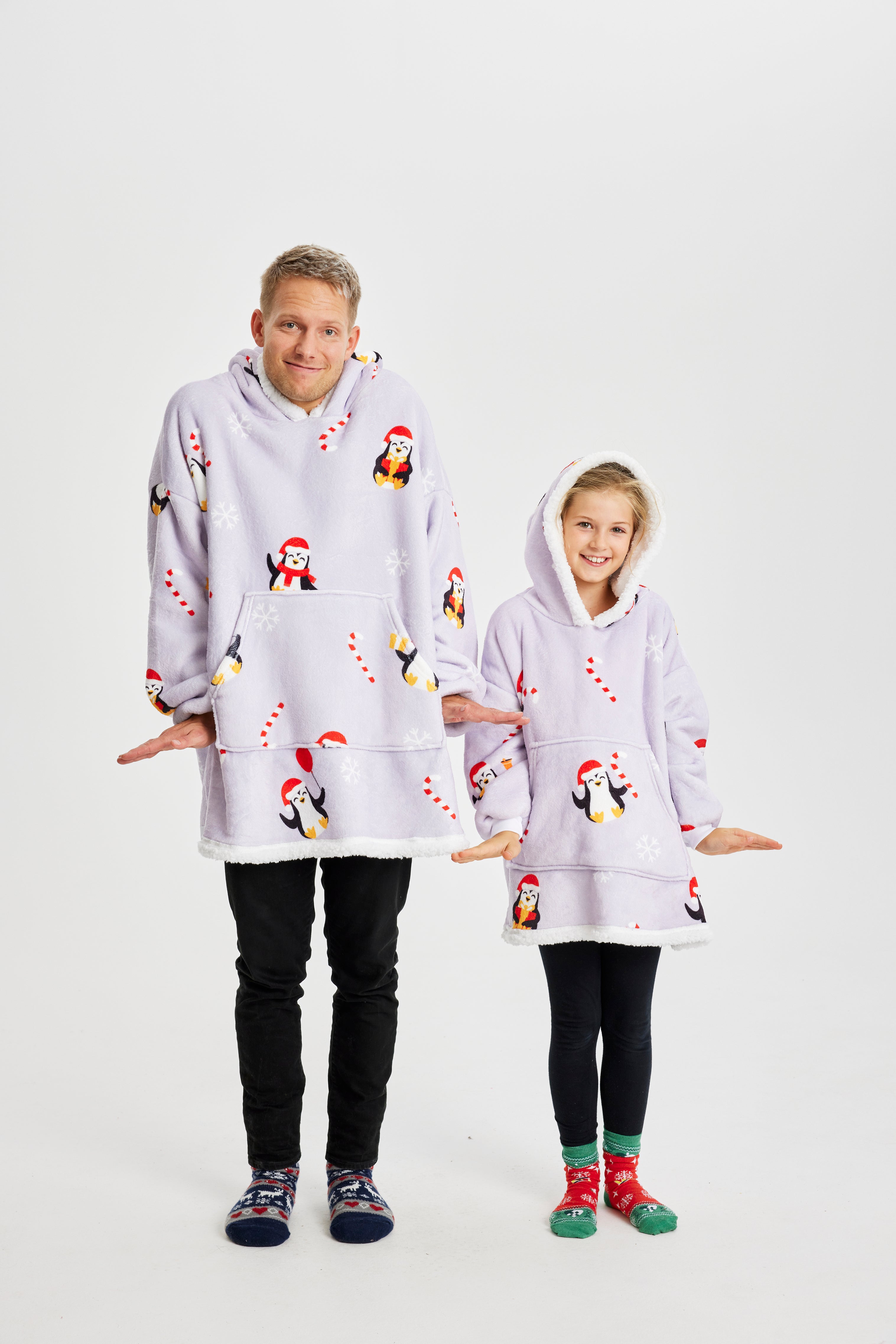Een man en een kind die een lichtpaarse kerst hoodie met pinguïns dragen.